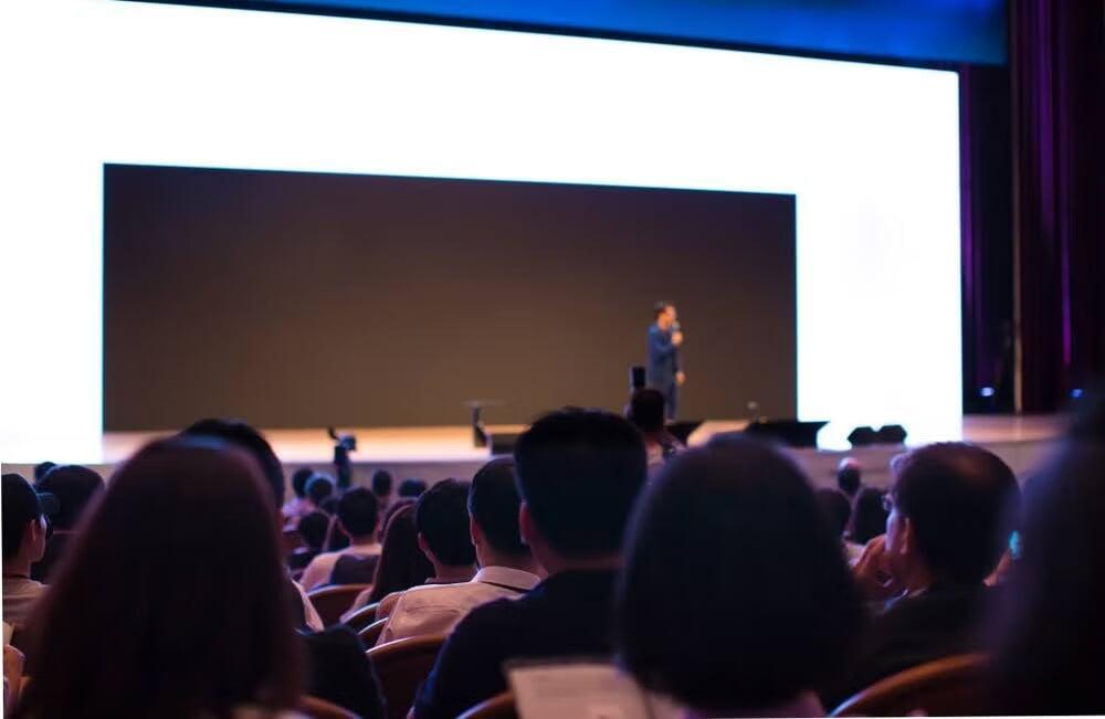 corporate event with people sitting and watching a speaker at a panel